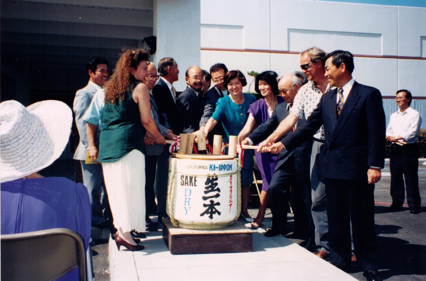 Board members and guests with mallets breaking open a sake barrel outside the new annex in 1994