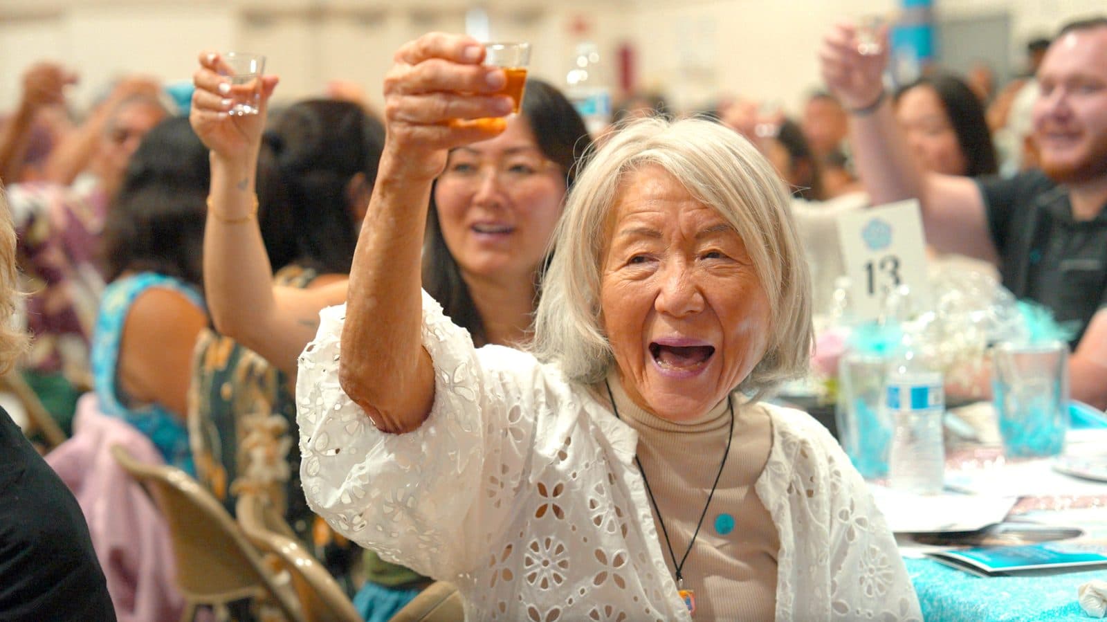 An older woman raising her glass in a joyful toast