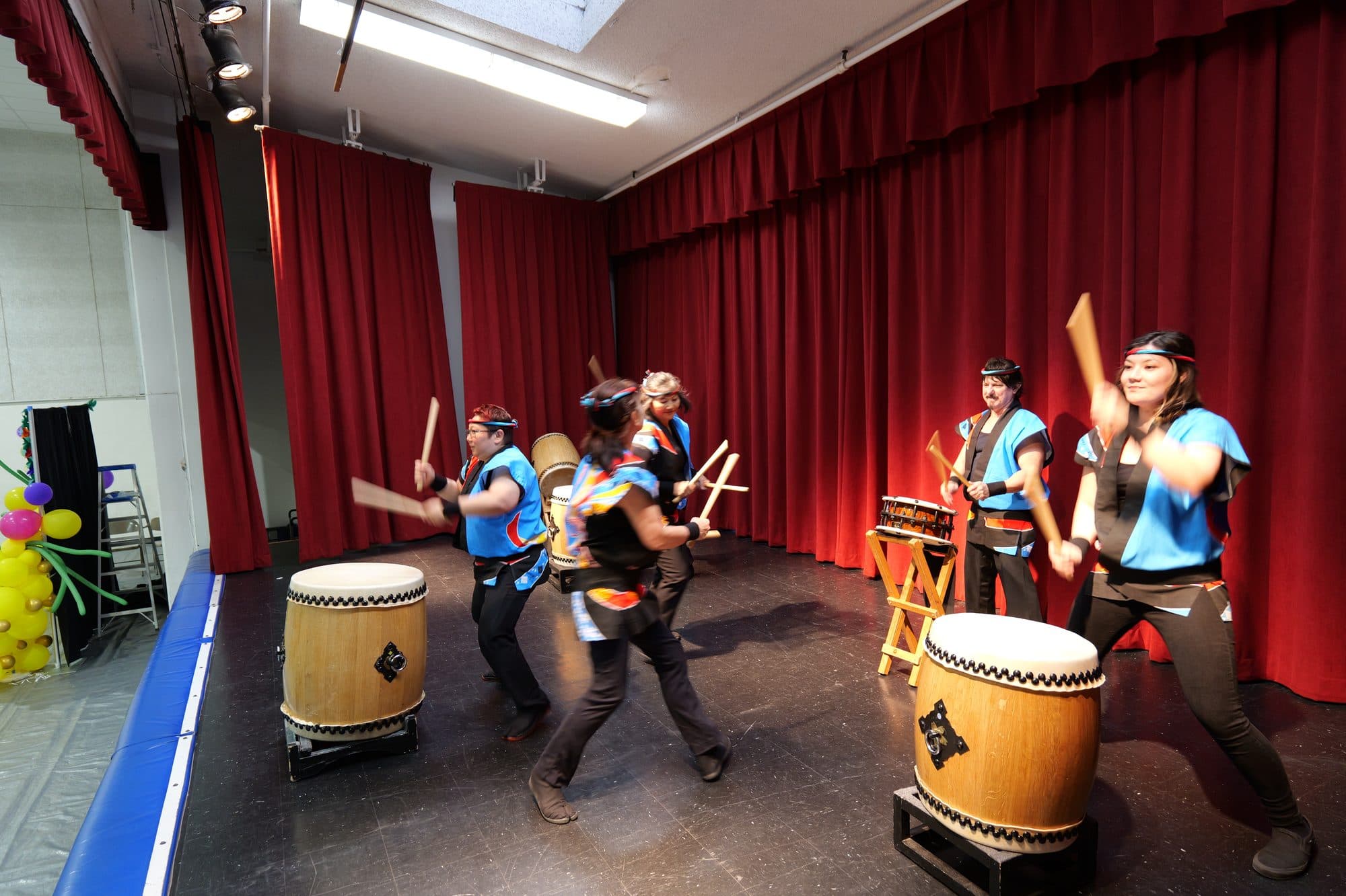 Taiko drummers striking their drums on the center's stage