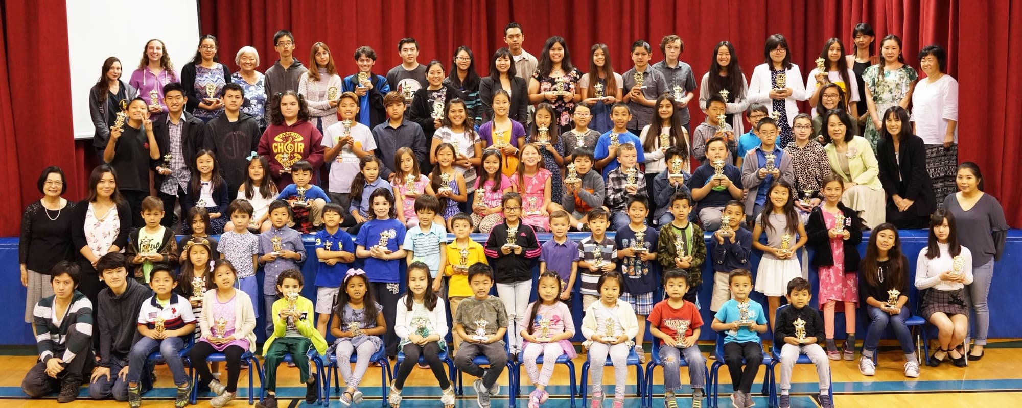 The whole school, students and teachers, on the gym stage with their trophies after the 2018 Ohanashikai speech contest
